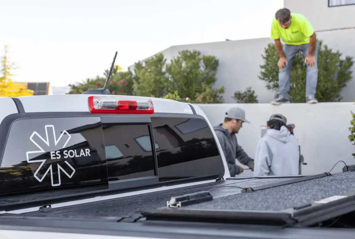 Truck with solar equipment and workers nearby.