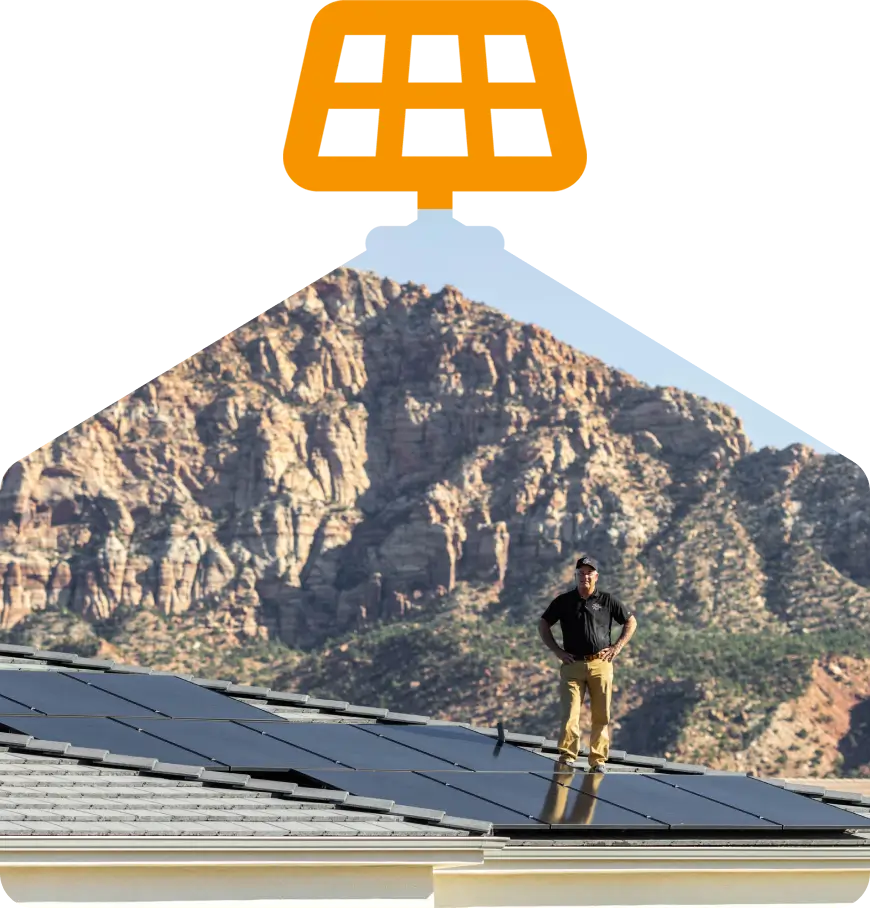 Man standing on rooftop solar panels, mountains.